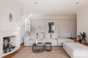 A modern living room with a sectional sofa, two black wire coffee tables, a fireplace, and a large mirror on the wall. - Exquisite 2BR Apartment (Agia Paraskevi)