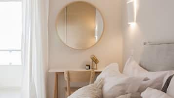 Une chambre à coucher comprenant un lit, un bureau, une chaise, un miroir rond et une lampe de chevet.