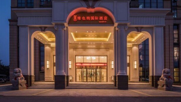 A hotel entrance with a grand archway, columns, and a sign in a foreign language. - Vienna International Hotel Kunshan Lujia Shentongyu Subway Station (Kunshan)