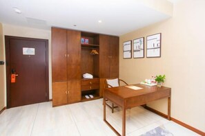 A hotel room with a wooden wardrobe, a table with a plant, and framed pictures on the wall. - Vienna International Hotel Kunshan Lujia Shentongyu Subway Station (Kunshan)