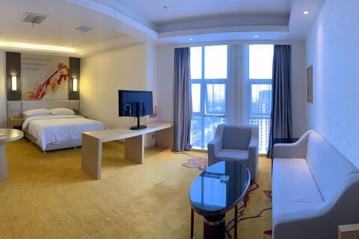 Una moderna camera d'albergo con un letto, una scrivania, un divano e una grande finestra con tende.