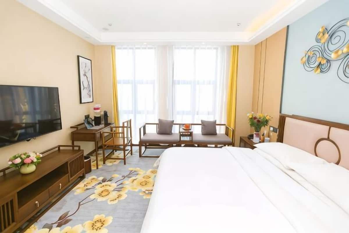 Una camera d'albergo con un letto, una televisione, una scrivania con una sedia e un divano.