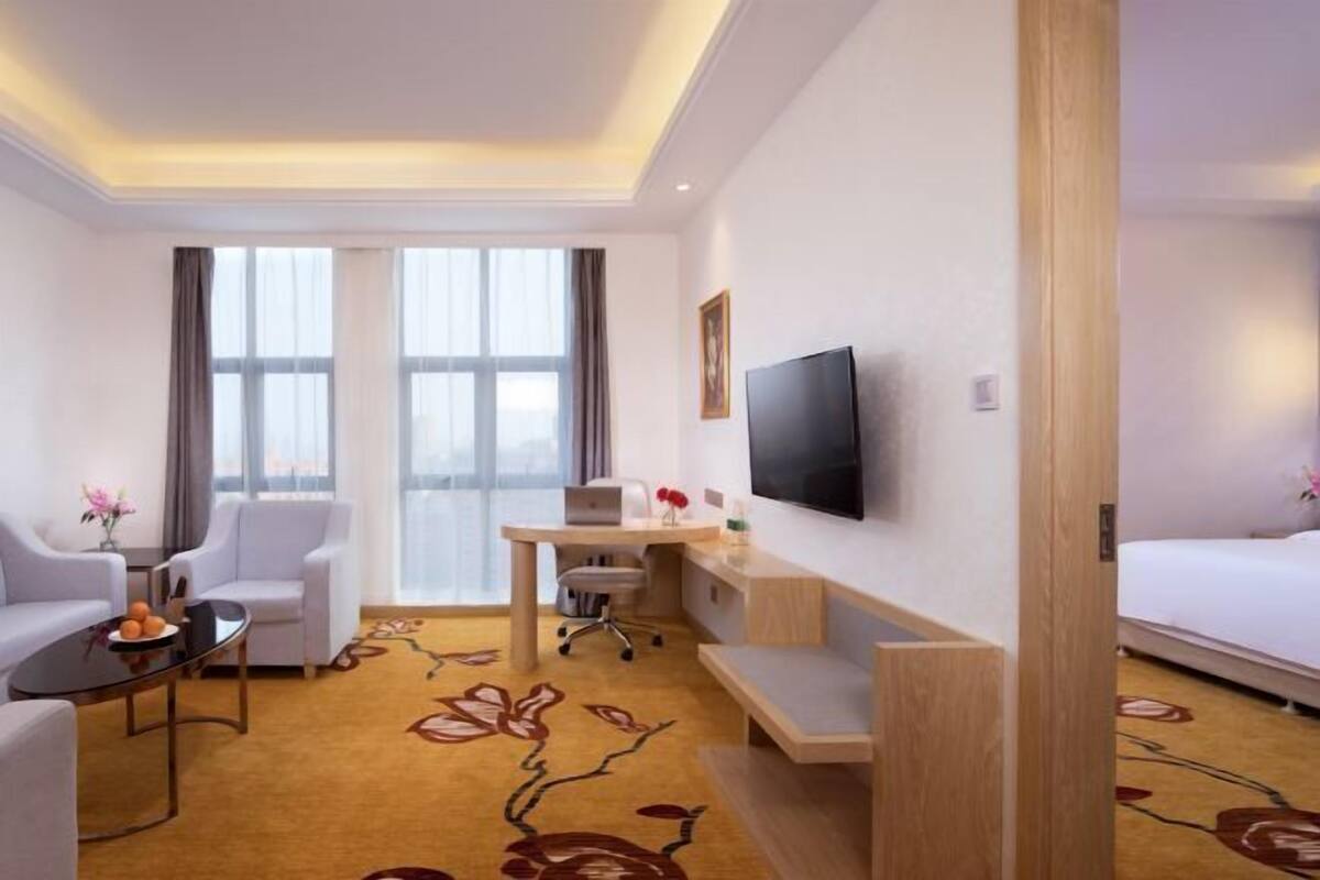 Una camera d'albergo con un letto, una scrivania con una sedia, un divano e una televisione.