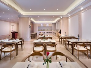 A hotel dining area with multiple tables and chairs, a podium, and decorative items. - Vienna International Hotel Kunshan Lujia Shentongyu Subway Station (Kunshan)