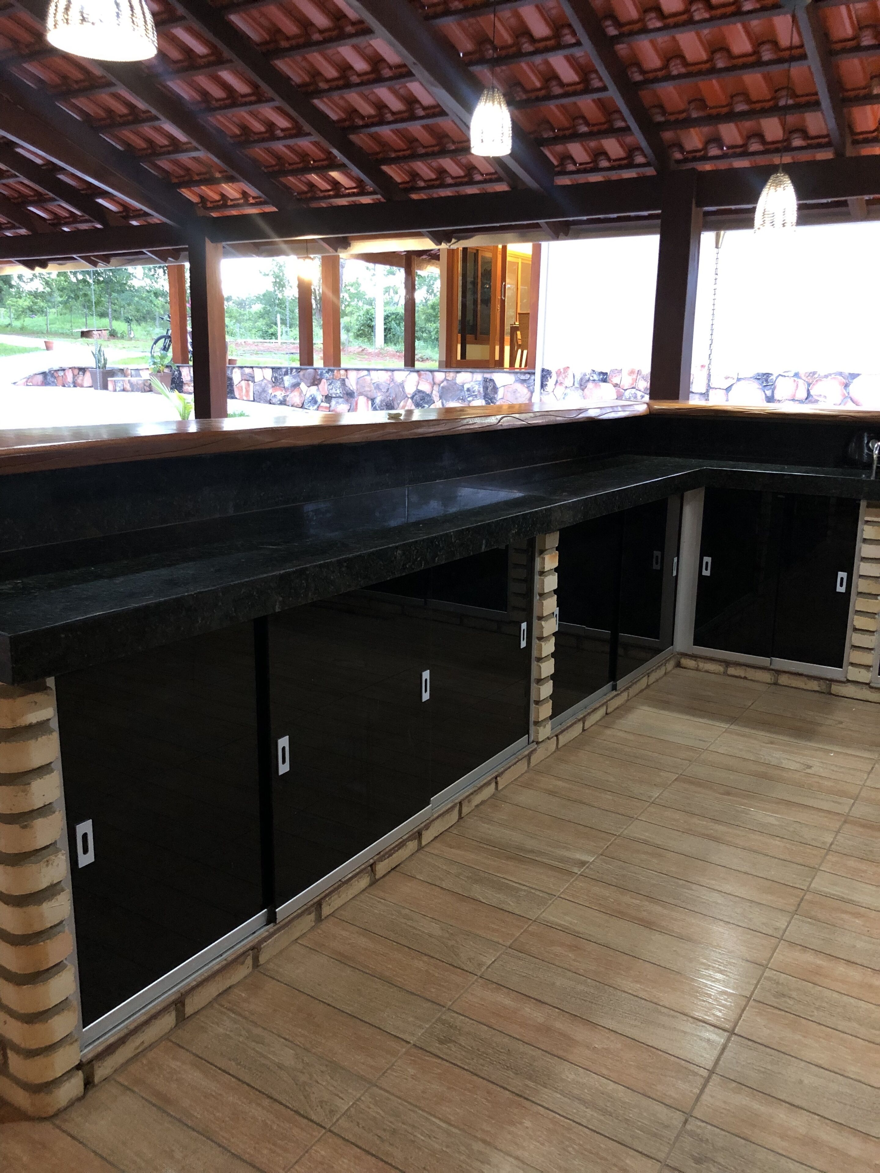 Un espace extérieur abrité, doté d’un sol carrelé en pierre et d’un comptoir noir.