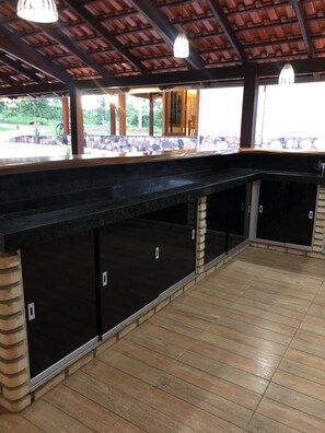 A covered outdoor seating area with a stone-tiled floor and a black countertop.