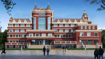 A large, multi-story building with a central tower and symmetrical design, featuring large windows and a spacious entrance area.