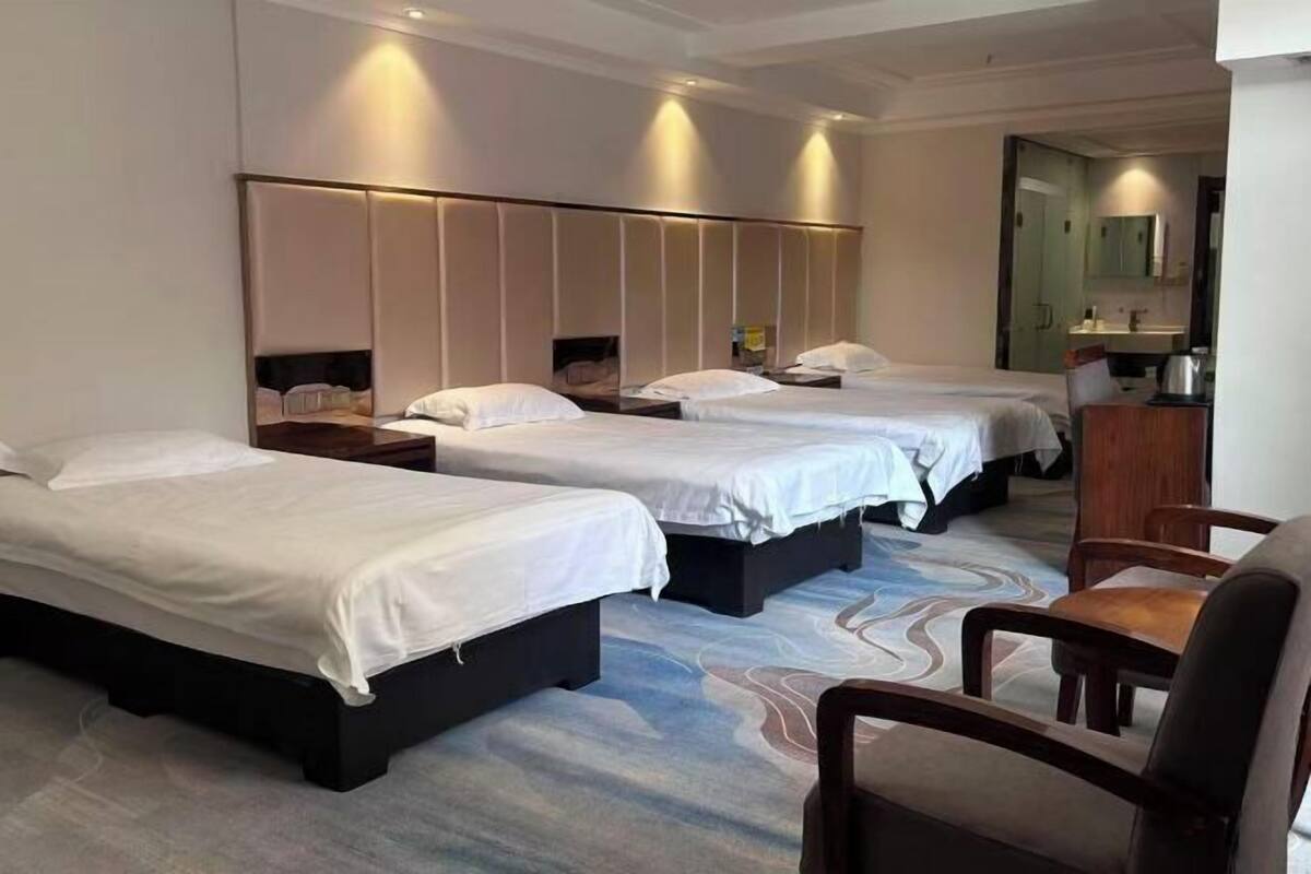 A hotel room with three beds, a desk, and a chair.