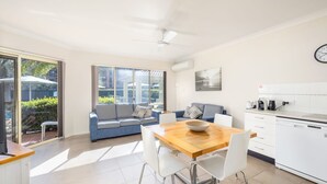A modern kitchen with a dining area, a sofa, and a view of the outdoors. - Marty's Little Beach No 5 (Nelson Bay)