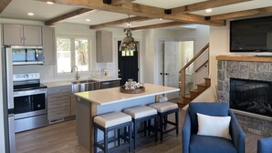 A modern kitchen with a central island, stainless steel appliances, and a stone fireplace. - Direct Waterfront Rental  (Lake George)
