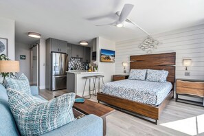 Un dormitorio moderno con una cama de madera, una pequeña kitchenette y un comedor.