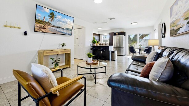A living room with a leather sofa, a coffee table, and a TV mounted on the wall.