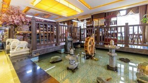 A traditional interior with wooden furniture, a stone lantern, and a decorative tree. - Yunxiang International Hotel (Wuwei)