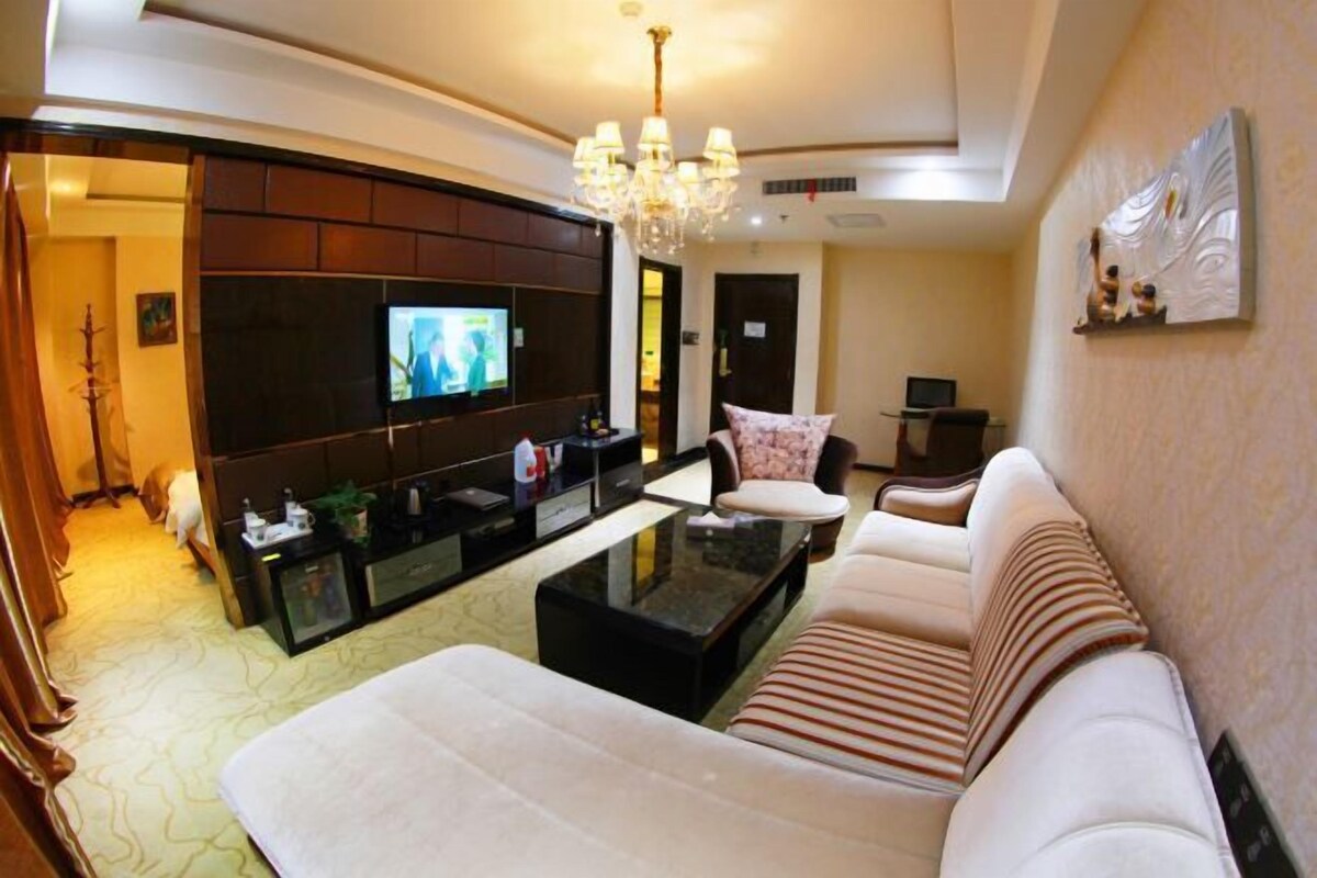 A modern living room with a sofa, a coffee table, a TV, and a chandelier.