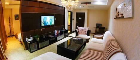 A modern living room with a sofa, a coffee table, a TV, and a chandelier.