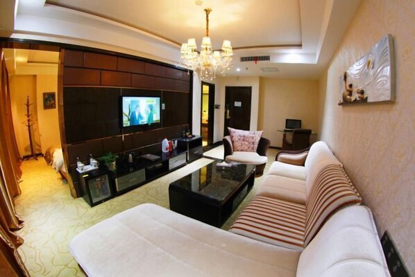 A modern living room with a sofa, a coffee table, a TV, and a chandelier.