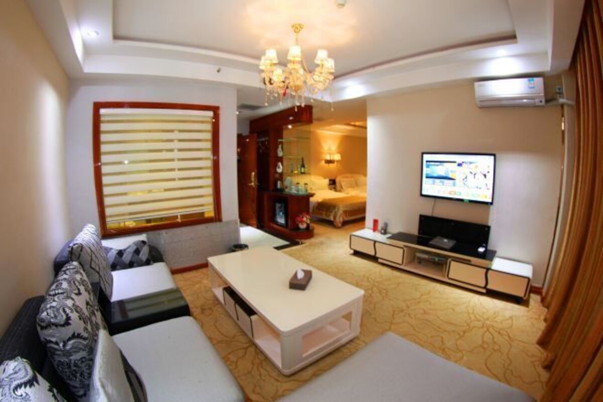 A modern living room with a sofa, coffee table, TV, and a chandelier.