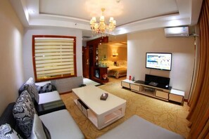 A modern living room with a sofa, coffee table, TV, and a chandelier.