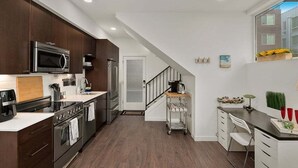 A modern kitchen with dark wooden cabinets, stainless steel appliances, and a white countertop. - Perch - Centro Guesthouse F: Walkable, Parking, Rooftop Deck & Pet Friendly (Seattle)