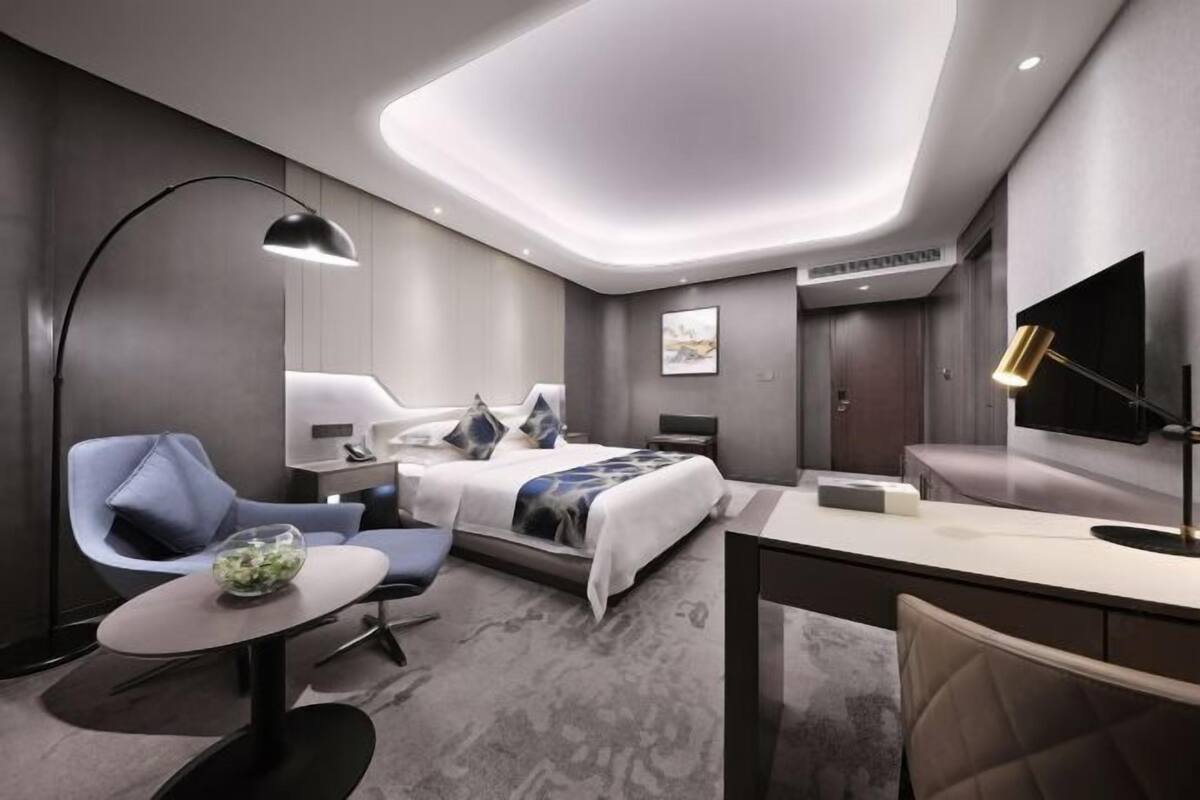 Een moderne hotelkamer met een bed, bureau, stoel en een televisie.