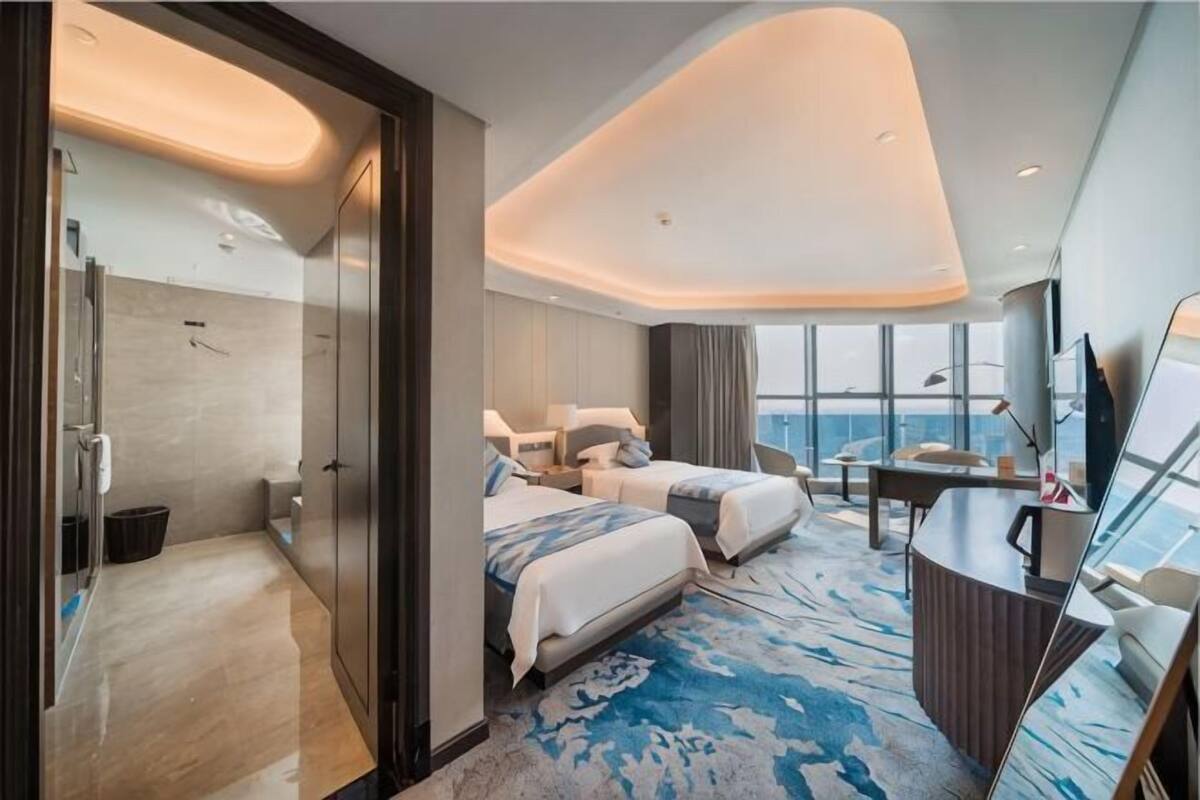 Een moderne hotelkamer met een groot bed, een bureau en uitzicht op de stad.