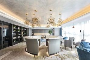 Een modern interieur met een zithoek, een boekenkast en een groot raam dat voor natuurlijk licht zorgt.