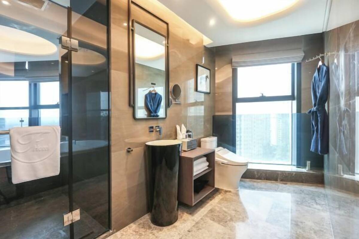 Een moderne badkamer met een douchecabine van glas, een grote spiegel, een wastafel met een wasbak en een toilet.