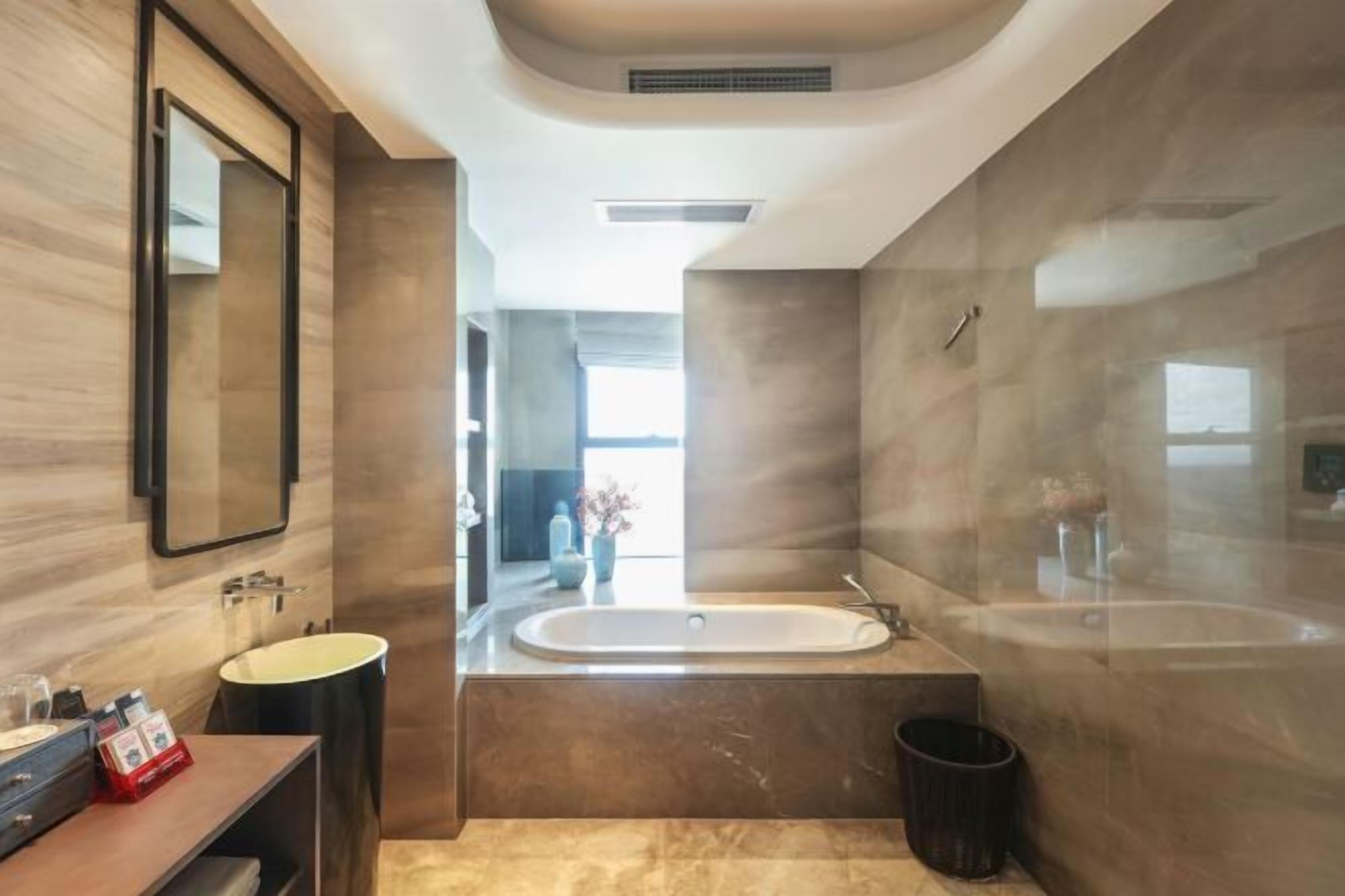 Un baño moderno con una bañera grande, un tocador con espejo y un lavabo.