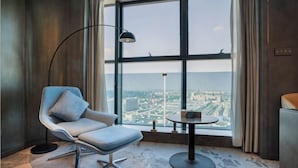 Ein modernes Zimmer mit großem Fenster, einem Sessel, einem kleinen Tisch und einer Stehlampe.