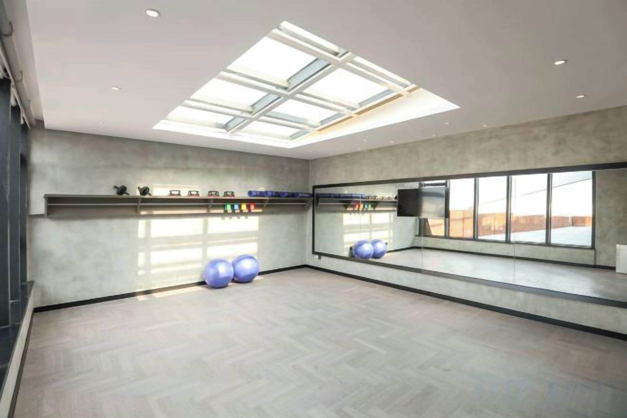 A spacious room with a skylight, exercise balls, and a large mirror.
