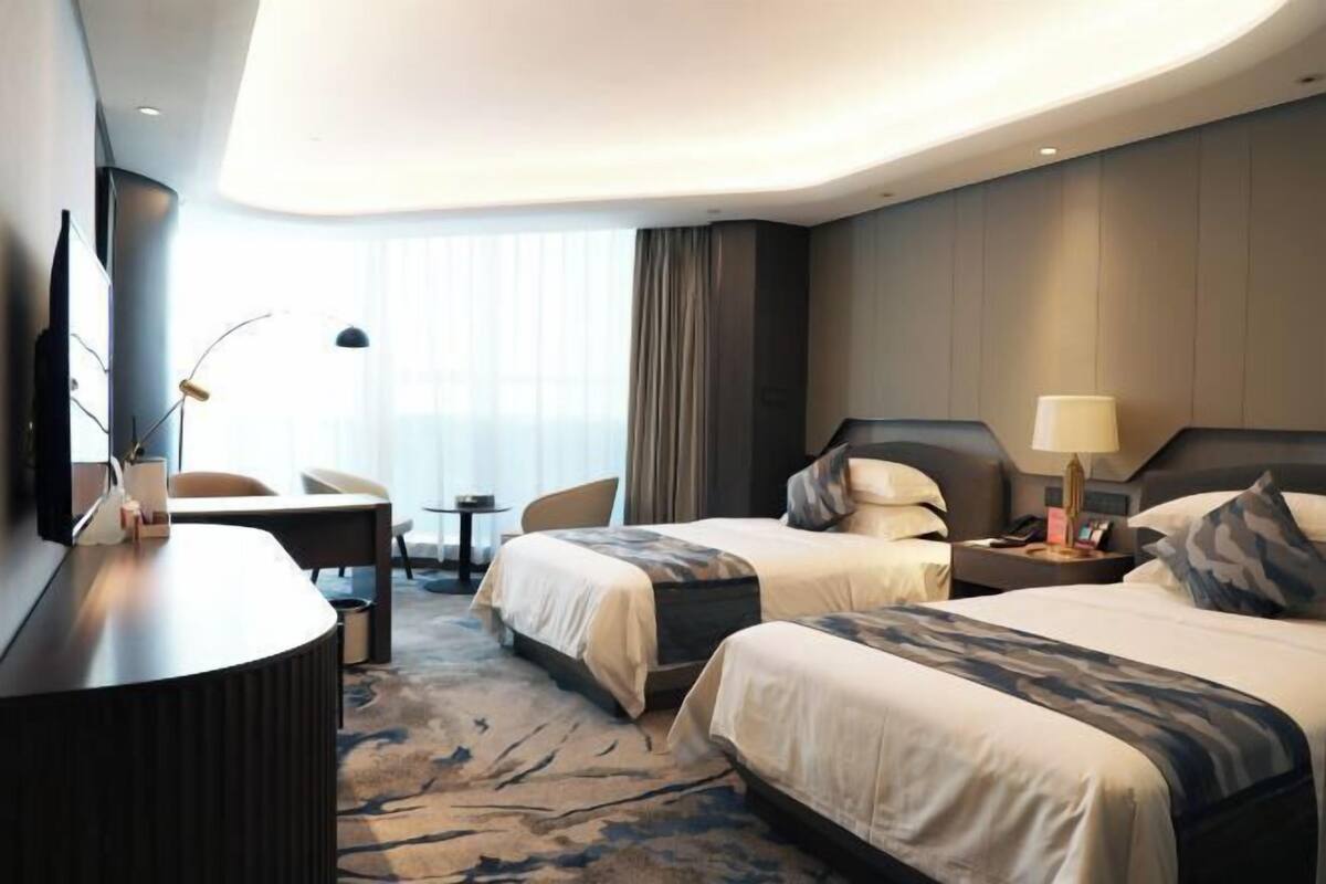 Een moderne hotelkamer met twee bedden, een bureau en een televisie.