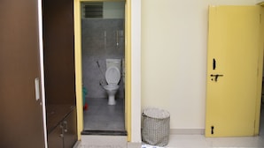 Un baño con un inodoro, un cubo de basura y una puerta amarilla.