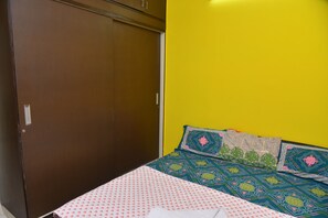 A bedroom with a bed, a wardrobe, and a yellow wall.