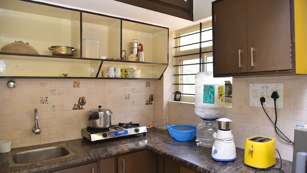 Una cocina con un lavamanos, estufa, tostadora y diversos utensilios de cocina sobre la encimera.
