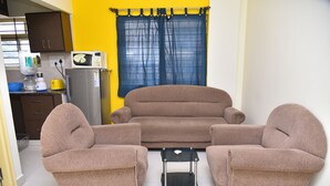 Una sala de estar con un sofá, una mesa de centro y un refrigerador.