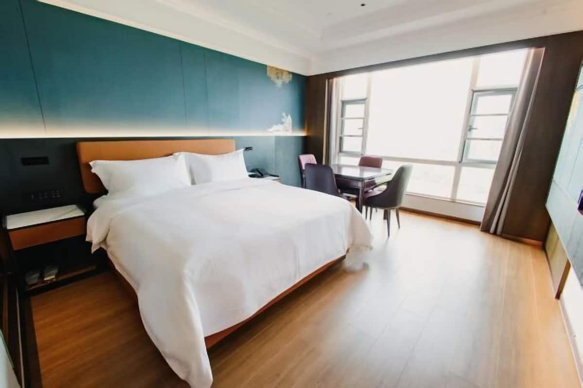 A hotel room with a large bed, a desk, and a chair.