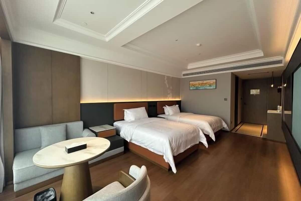 A hotel room with a bed, a sofa, a small table, and a door leading to a bathroom.
