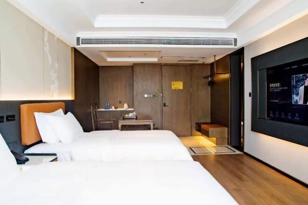 A hotel room with a large bed, a desk, a TV, and a ceiling fan.
