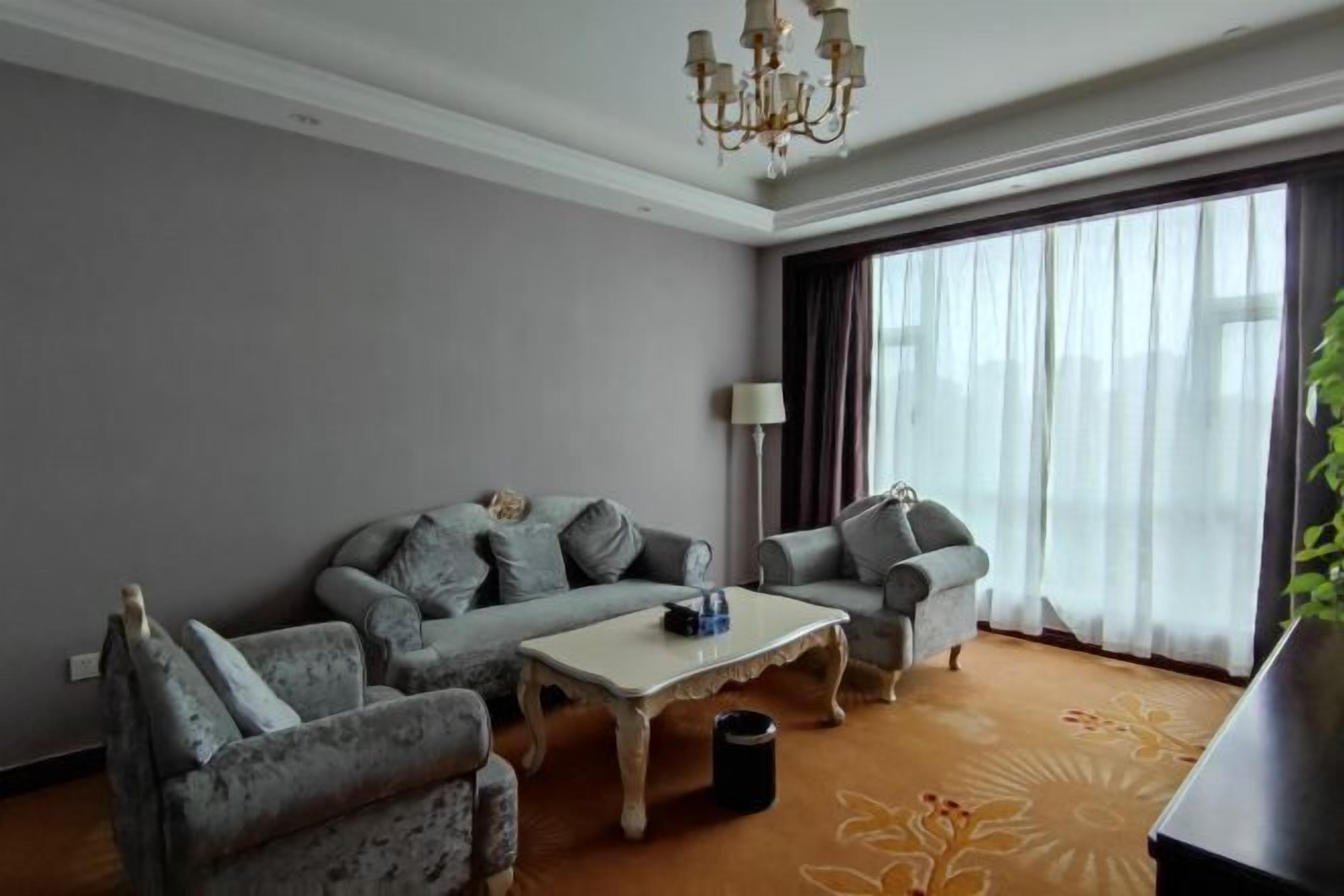 A modern living room with grey sofas, a white coffee table, and a chandelier.