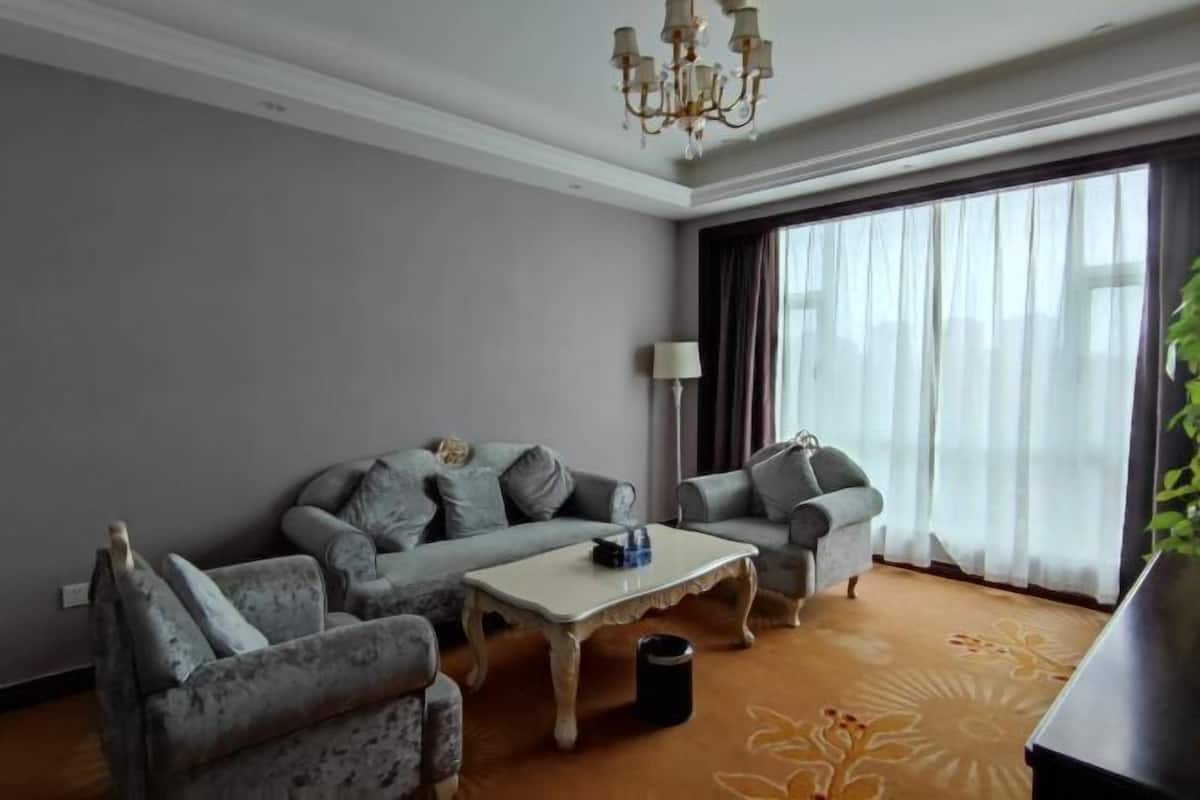 A modern living room with grey sofas, a white coffee table, and a chandelier.