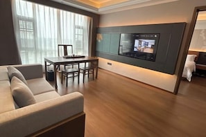 Una sala de estar moderna con un sofá, una mesa de comedor y un televisor montado.