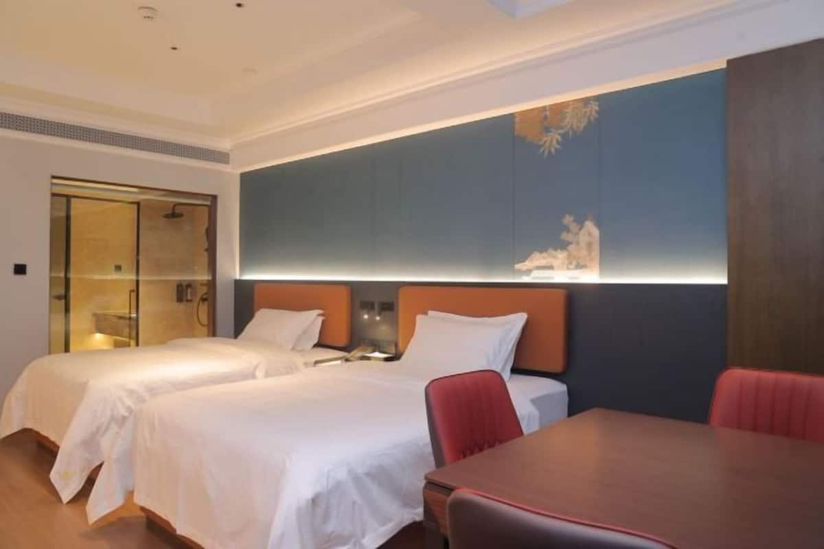 A hotel room with two beds, a shower area, a dining table, and a large wall mural.
