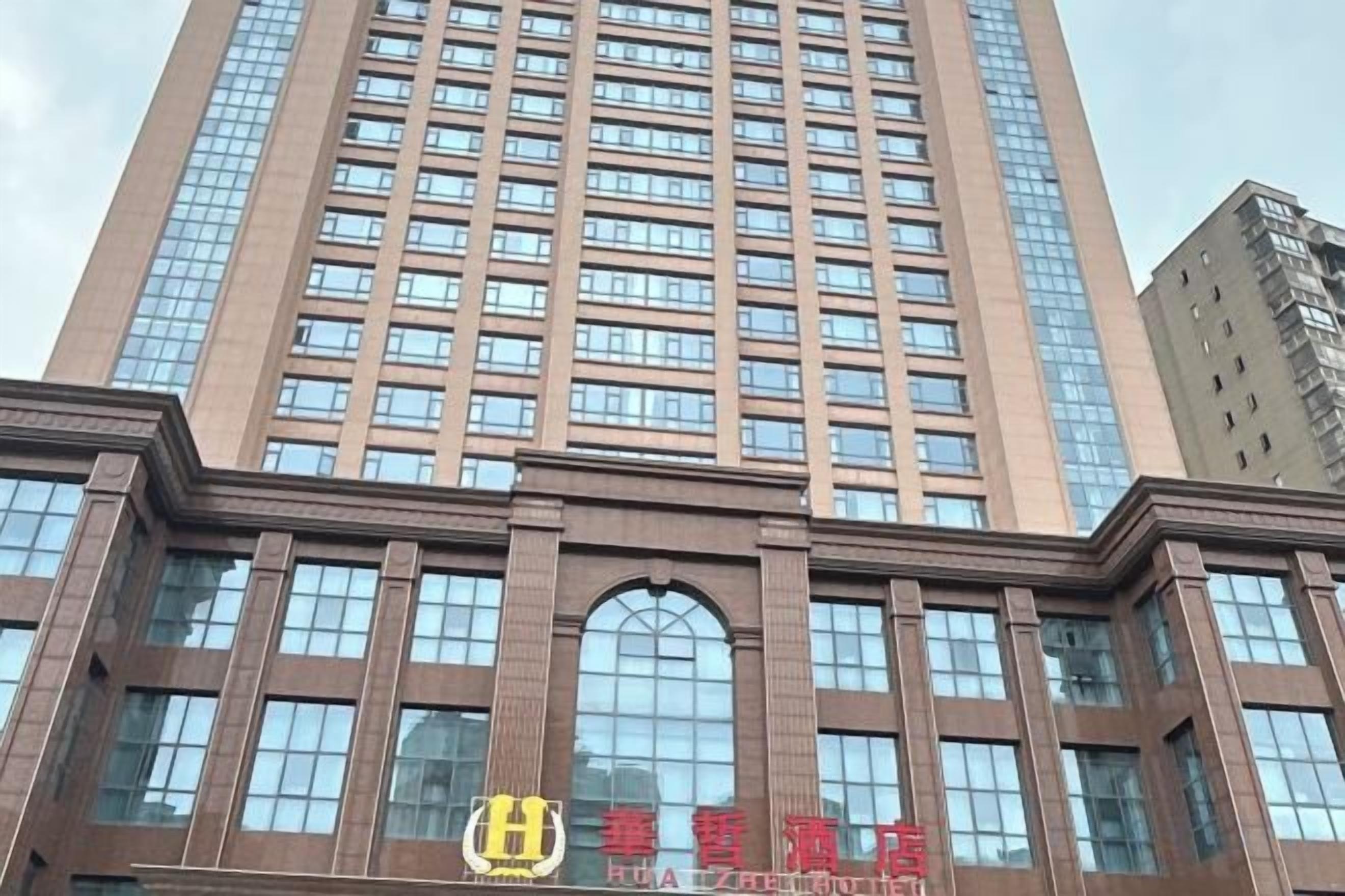 A tall building with a modern architectural design, featuring a series of windows and a prominent entrance with a sign.