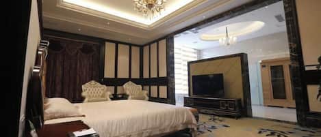 A hotel room with a large bed, a TV, a chandelier, and a view of the outside.
