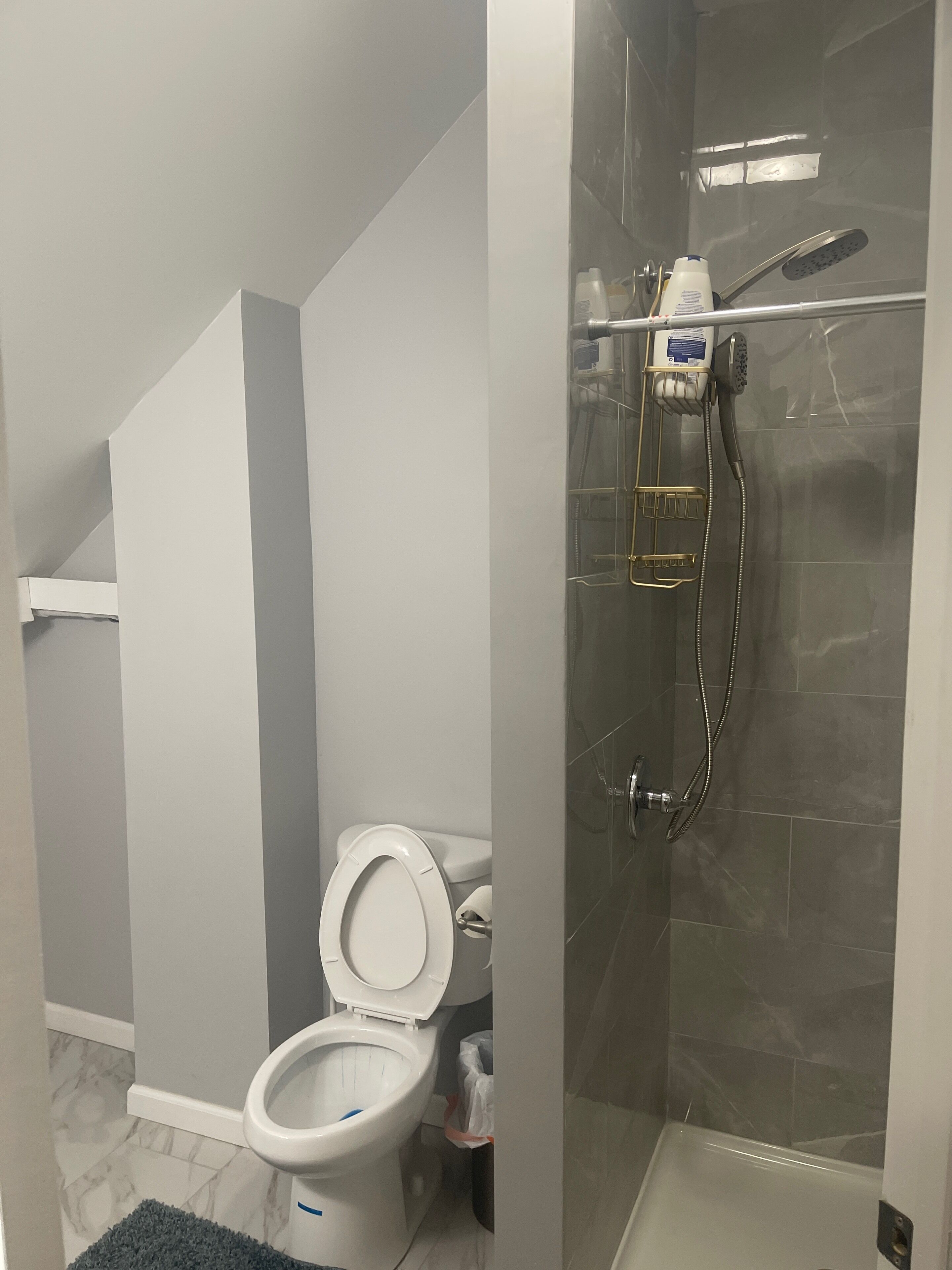Un baño con inodoro, cabina de ducha y suelo de mármol.