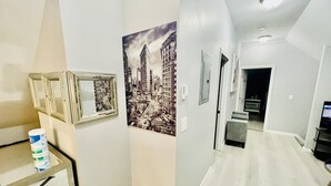 A hallway with a cityscape mural, a table with a paint can, and a door leading to another room. - Kid friendly neighborhood!  Everyone is welcomed in this cozy apartment home! (Springfield)