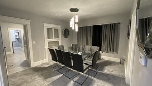 A dining area with a glass table and chairs, a pendant light, and a view of a hallway. - Kid friendly neighborhood!  Everyone is welcomed in this cozy apartment home! (Springfield)