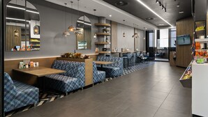 Un restaurant modern amb seients de disseny blau, il·luminació penjant i una pantalla de televisió.