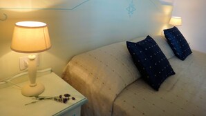 Un lit bien fait, avec deux oreillers, une lampe de chevet et une lampe fixée au mur.