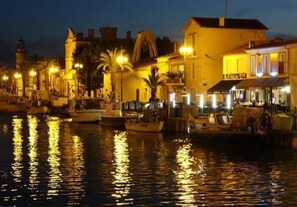 A waterfront area with boats docked, buildings with balconies, and street lamps along the water.